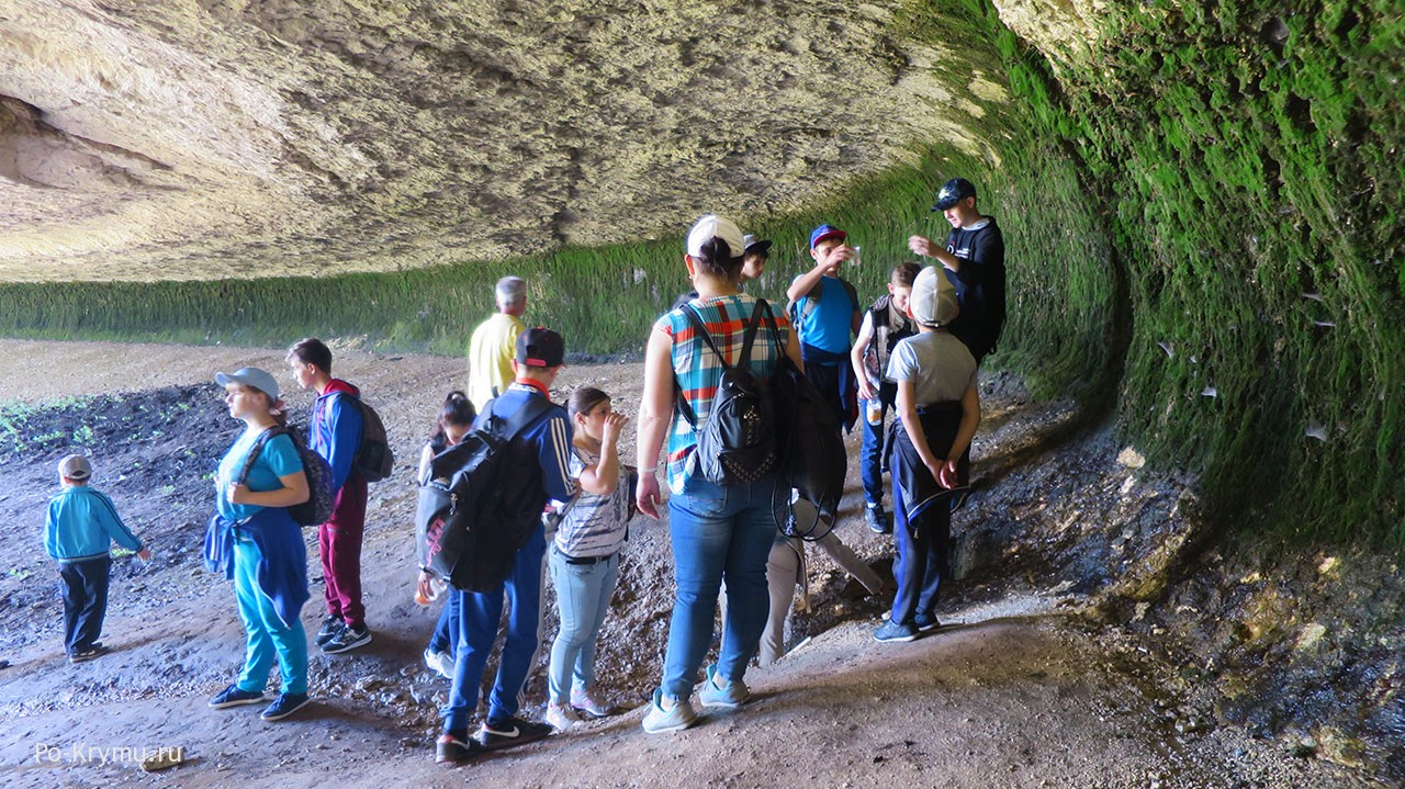 Туристы ловят капли воды, падающие с потолка пещеры.